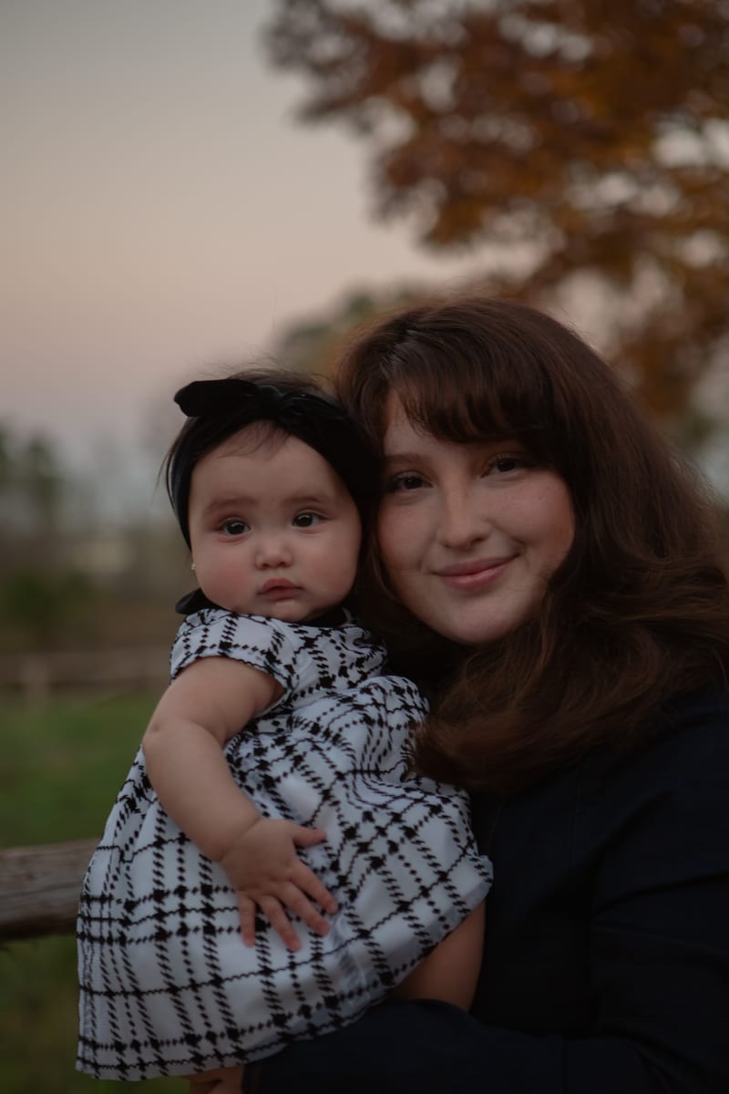 A mother holding her baby at sunset