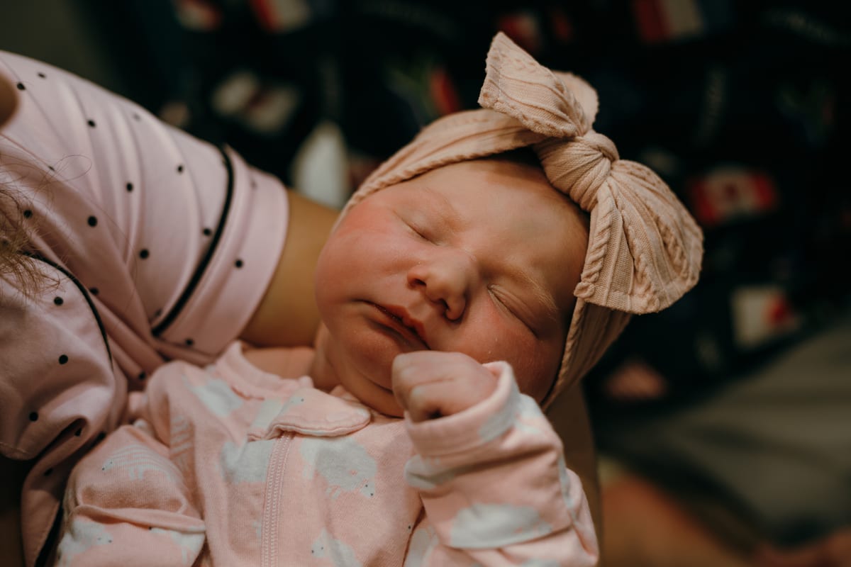 A sleeping newborn in a knit bow