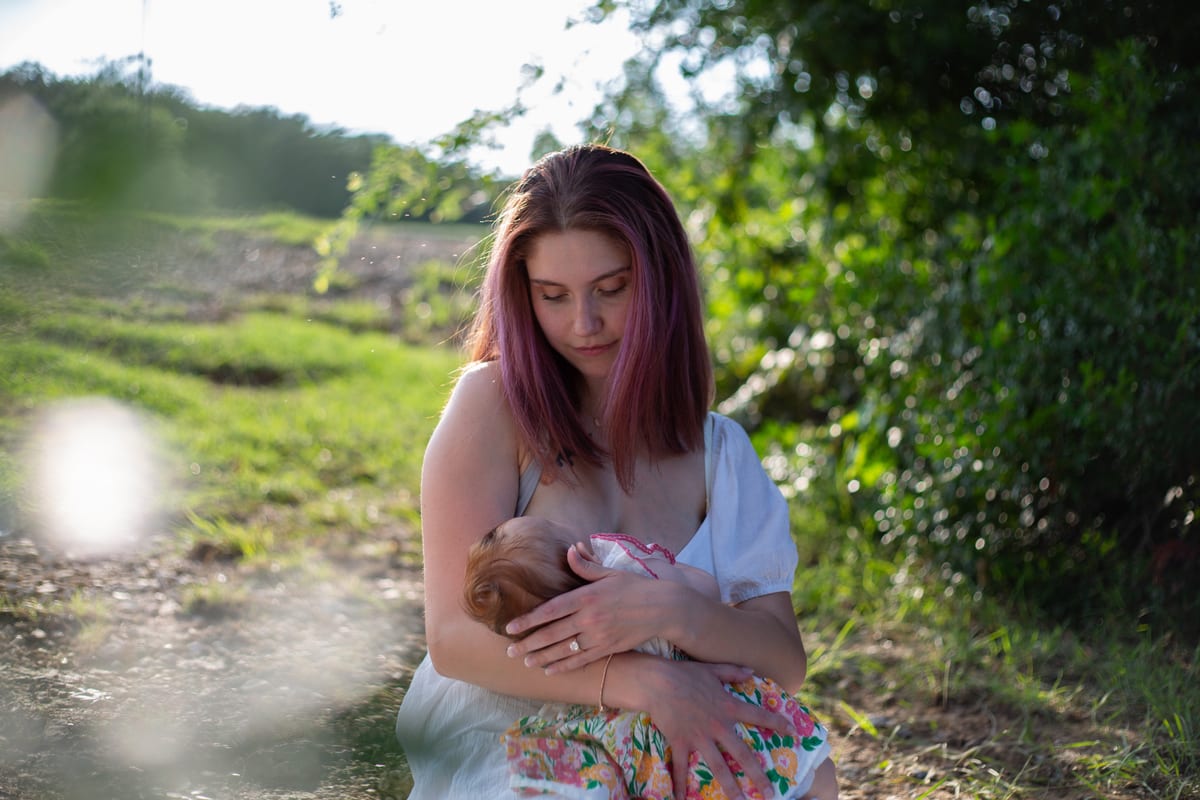 A mother holding her baby in a green field