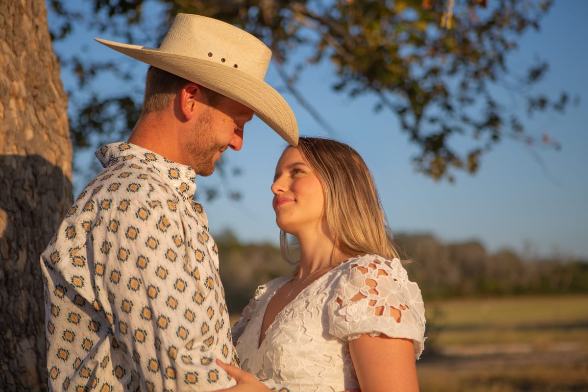 A couple in a golden field, he in a cowboy hat