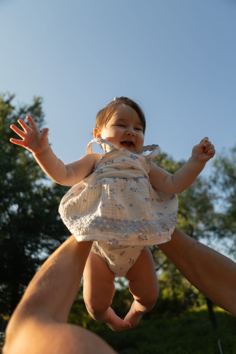 A baby lifted up into a blue sky