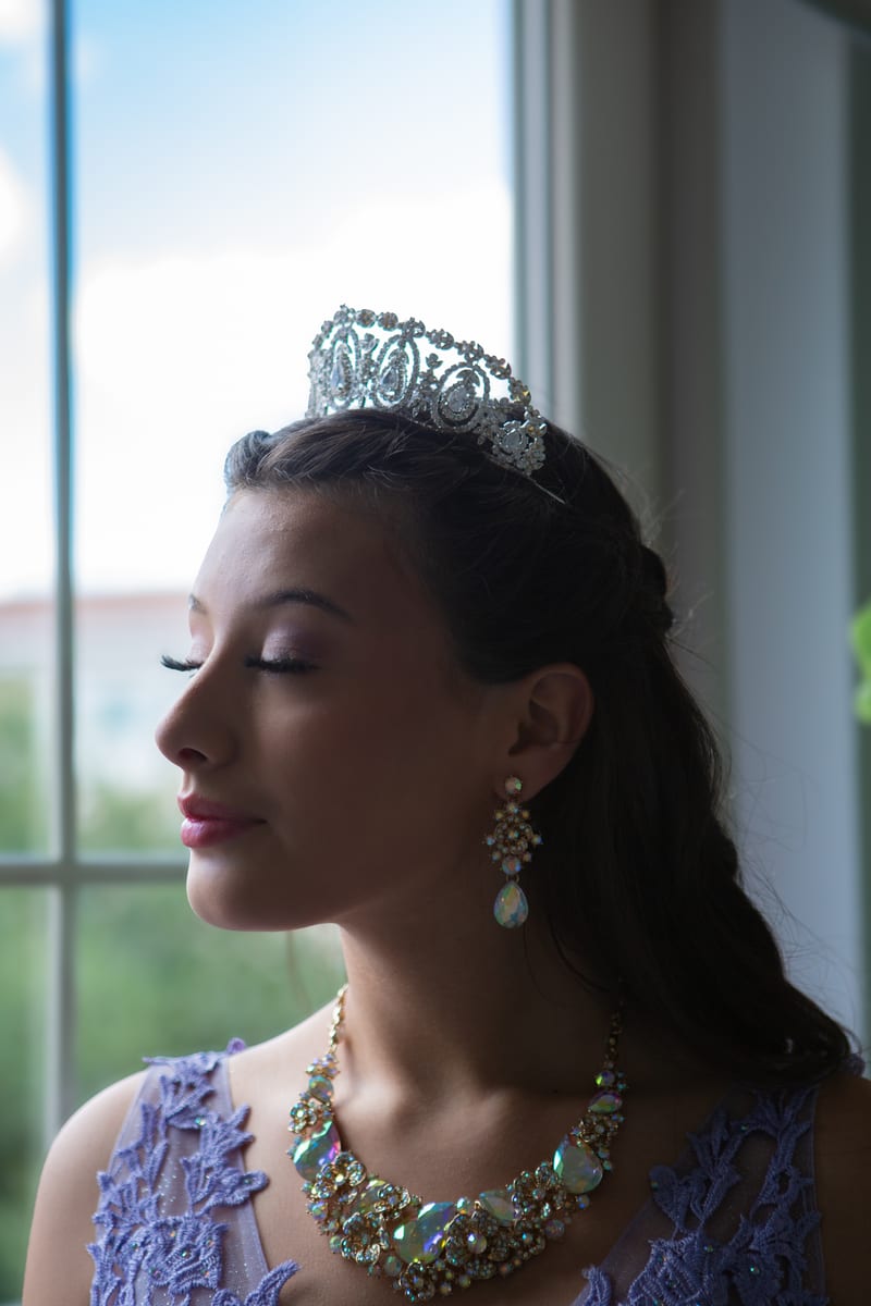 A girl in a tiara looking out of a window