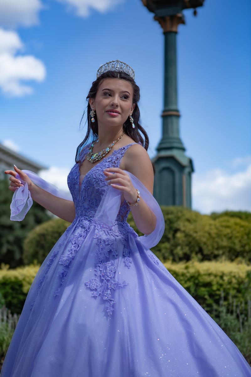 A girl in a purple gown and tiara in a garden