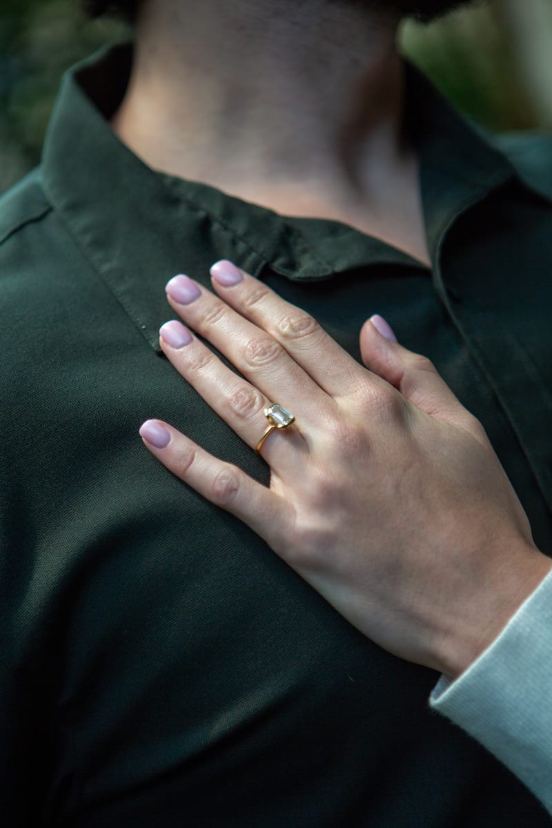A hand with an engagement ring resting on his chest