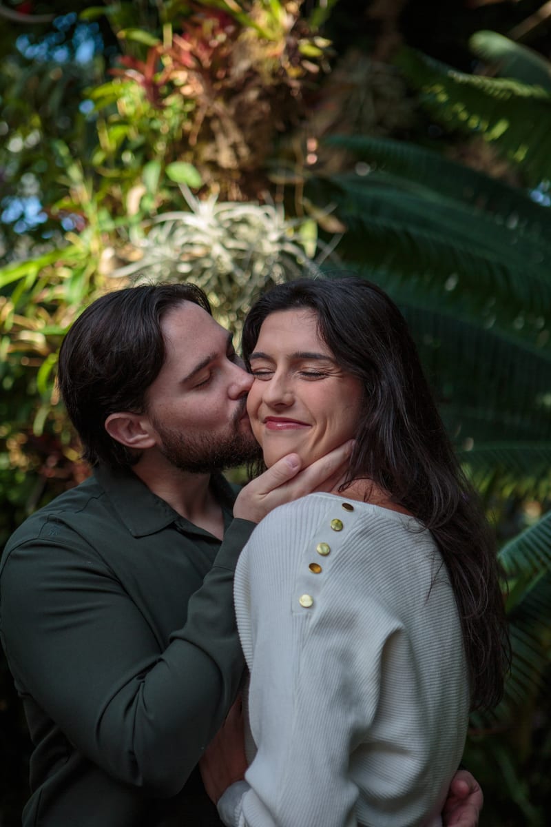 A couple kissing, surrounded by greenery