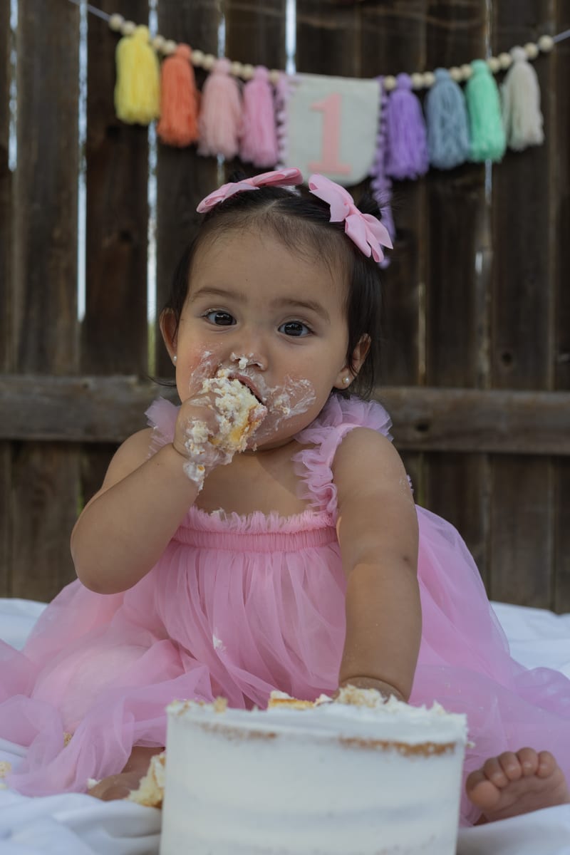 A baby digging into her first birthday cake