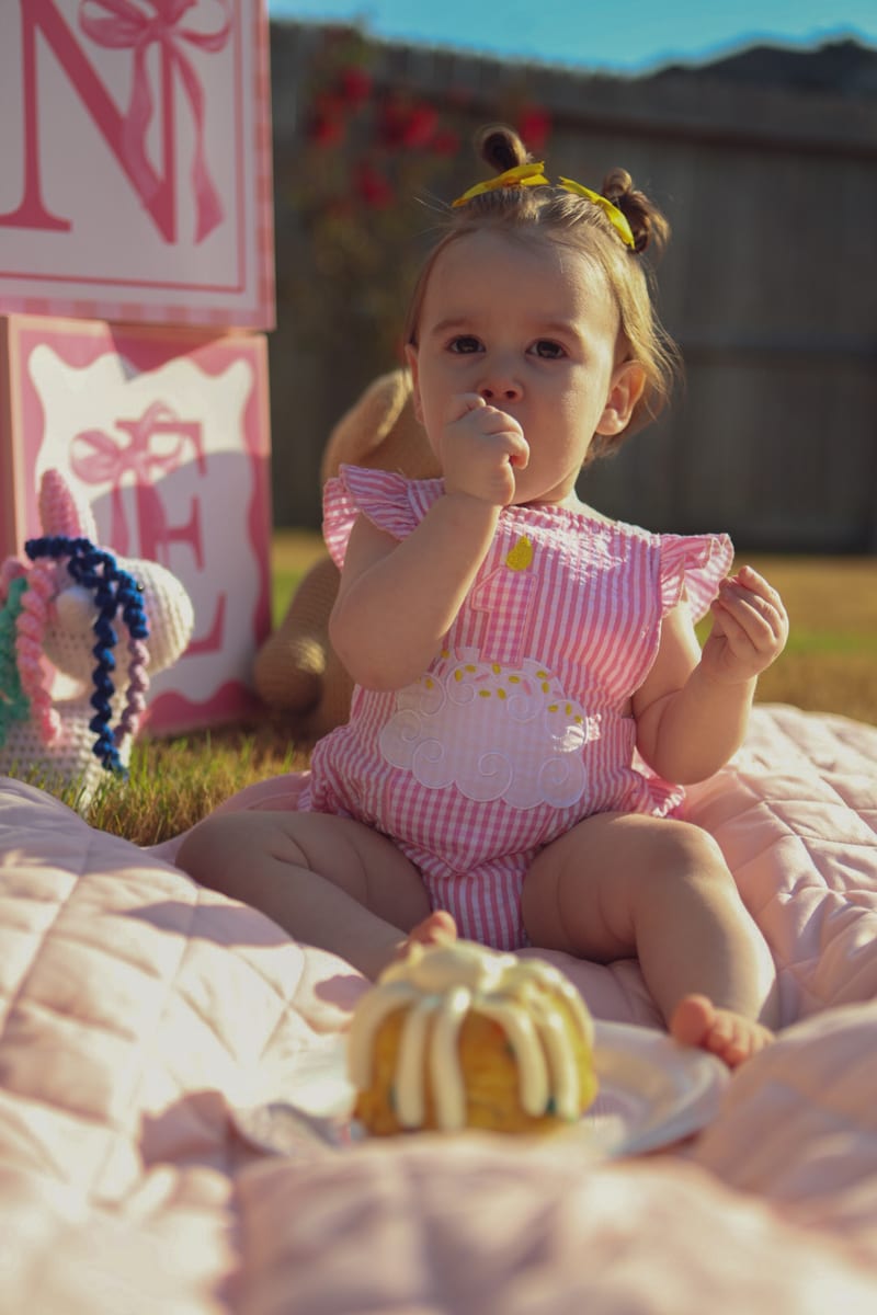A baby on a picnic blanket beside letter blocks