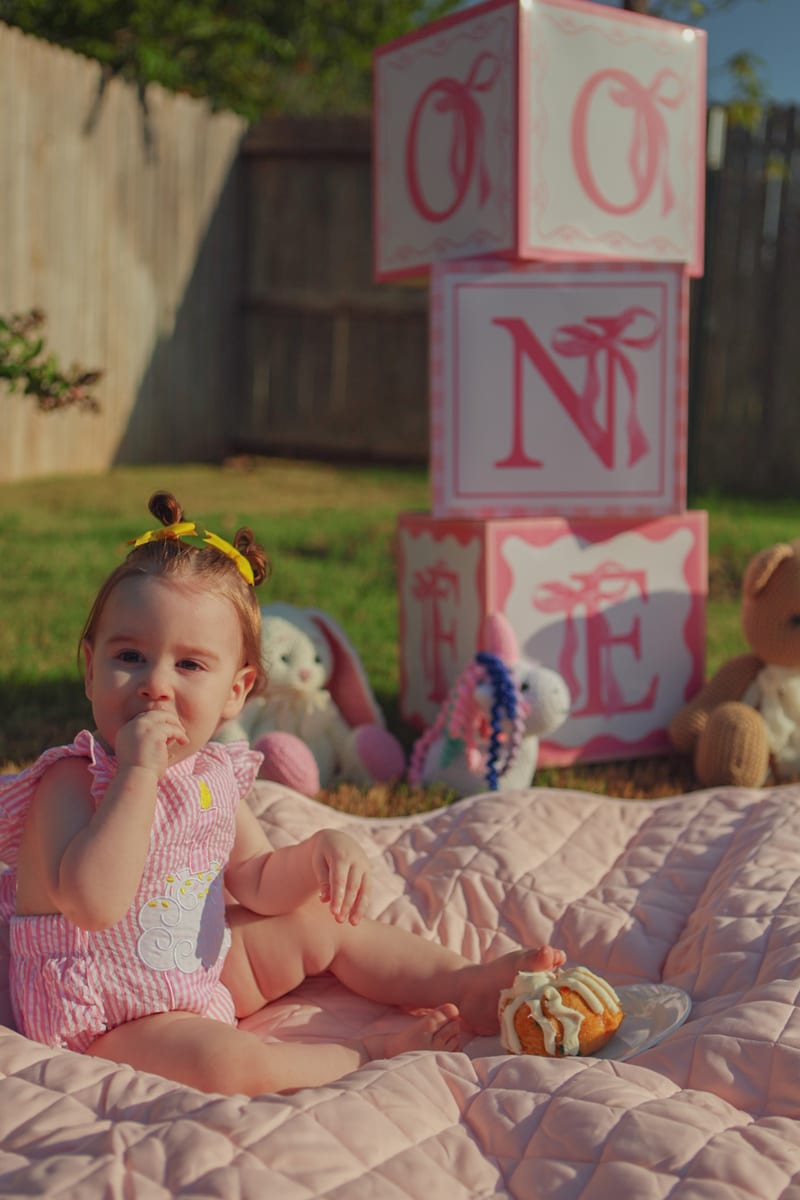 A baby eating cake on a picnic blanket