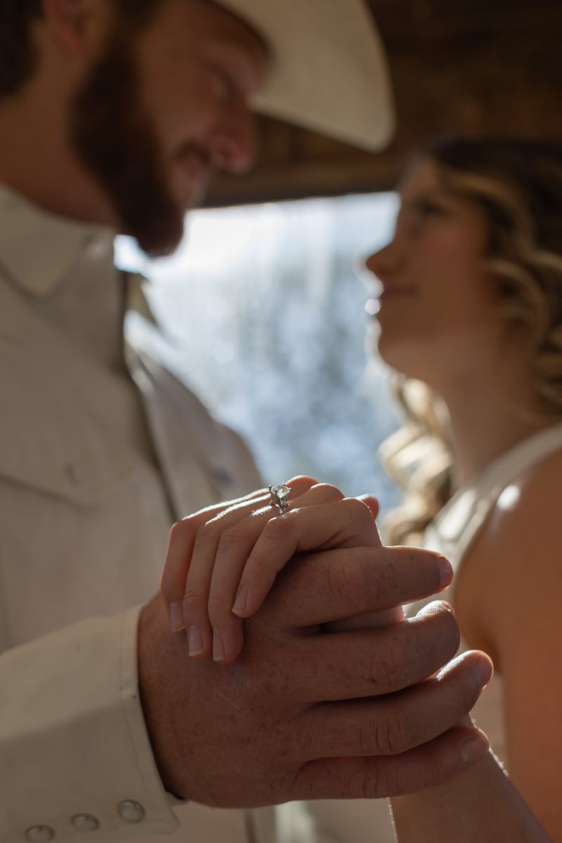 A couple’s hands clasped, showing the ring