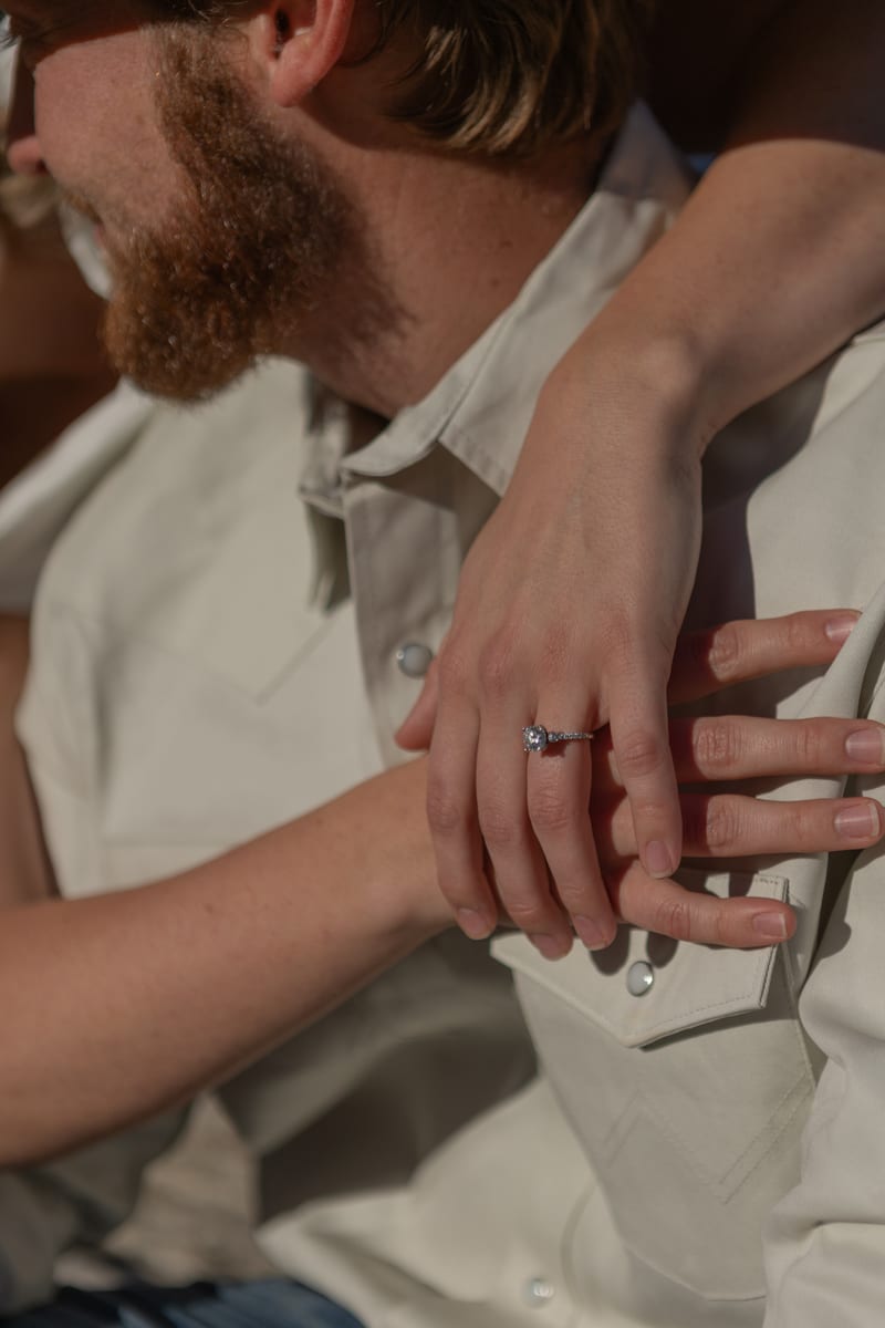 Close-up of hands clasped, showing an engagement ring