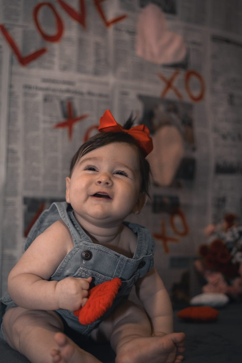 A baby in a red bow, laughing