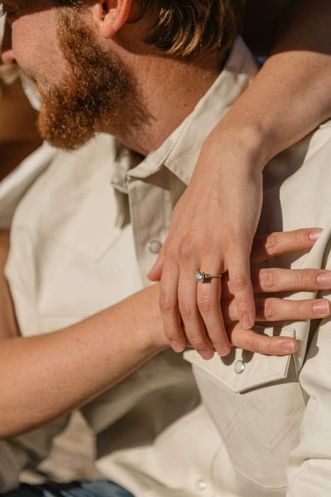 Close-up of hands clasped, showing an engagement ring